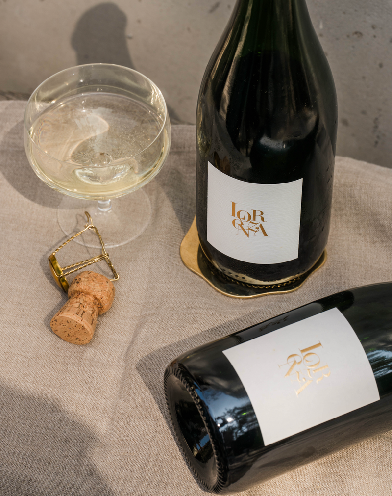 Two bottles of Lorenza Sparkling Picpoul with a full coupe and cage and cork close up