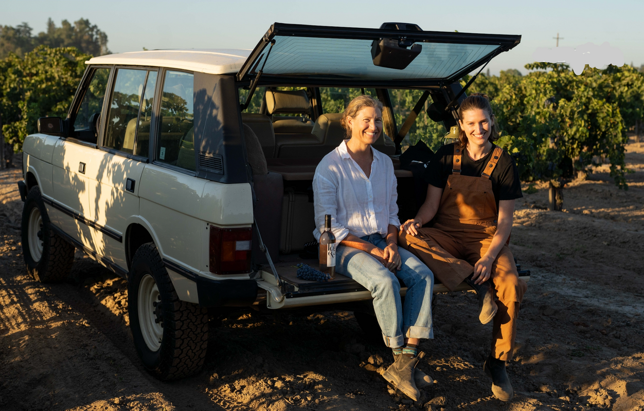 Melinda and Michele sitting in the back of a white Range Rover in a Carignan Vineyard.